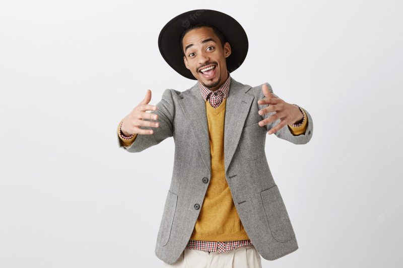 Come closer, let me hug you. positive friendly African-American man in trendy outfit and hat pulling hands towards Free Photo