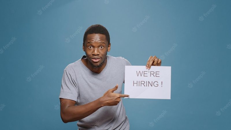 Company employee showing hiring application sign on paper, advertising job offer and career opportunity to hire candidate. office worker preparing for interview with applicant, hr recruitment. Free Photo