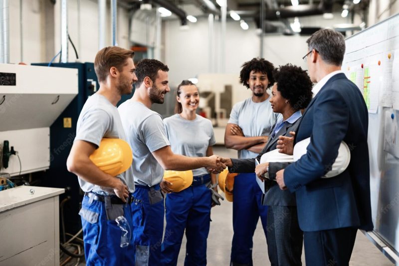 Company managers visiting their employees in a factory happy african american businesswoman is shaking hands with one worker Free Photo