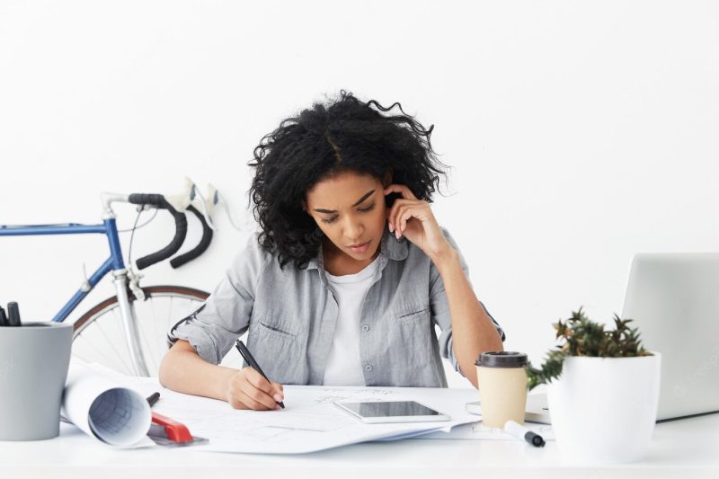 Concentrated serious young African American female architect making drawings Free Photo