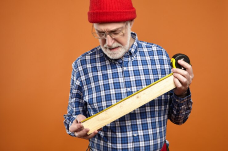 Concentrated Unshaven Retired Carpenter Wearing Red Knitted Hat Tool Belt Plaid Shirt Making Furniture Holding Wooden Plank Measuring Tape Craft Job Occupation Age Retirement 343059 2724