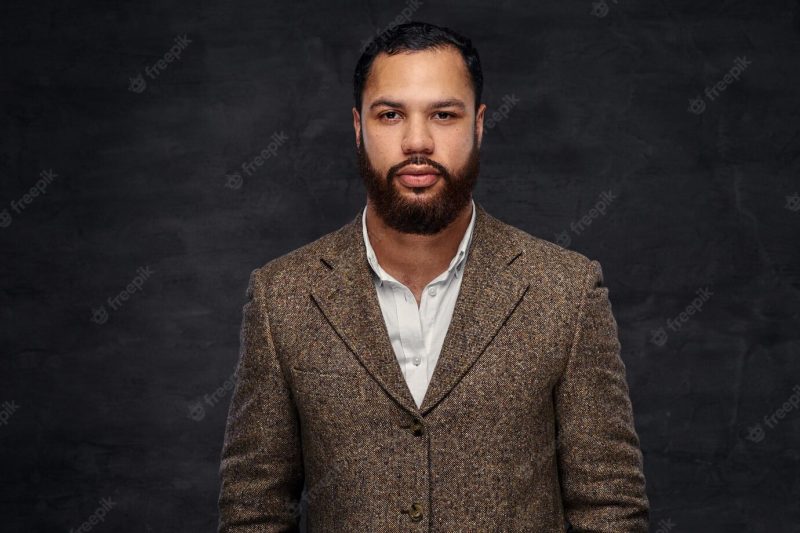 Confident african-american businessman in a brown classic jacket. isolated on a dark background. Free Photo