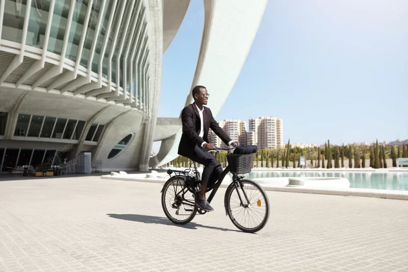 Confident eco friendly dark-skinned ceo using two wheeled pedal assist vehicle to get to work. successful modern black businessman riding bicycle to office after lunch . people, transport and business Free Photo