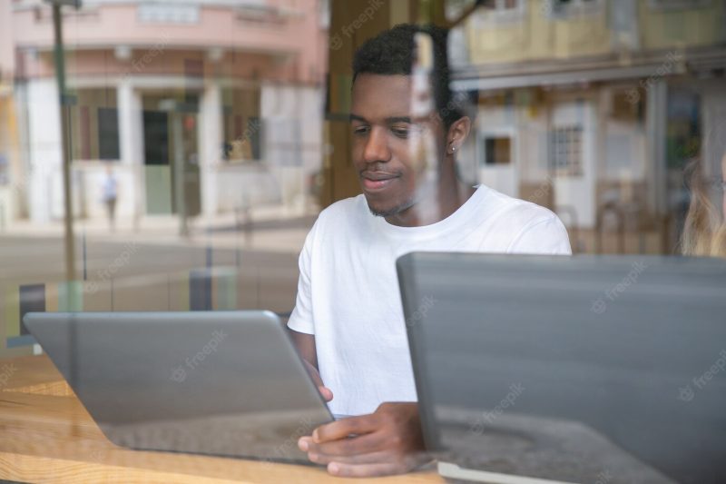 Content African American guy sitting at table and using laptop Free Photo