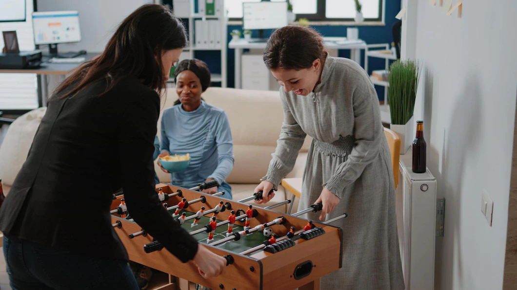 Corporate Workmates Using Foosball Table Play Soccer Game Playing After Work Office Colleagues Drinking Bottles Beer Alcohol While Enjoying Activity Have Fun 482257 34903