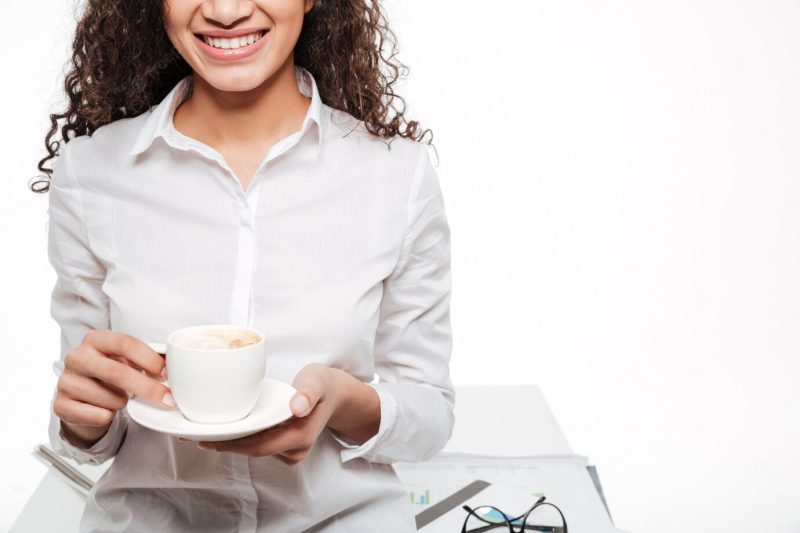 Cropped photo of happy African business woman drinking coffee Free Photo