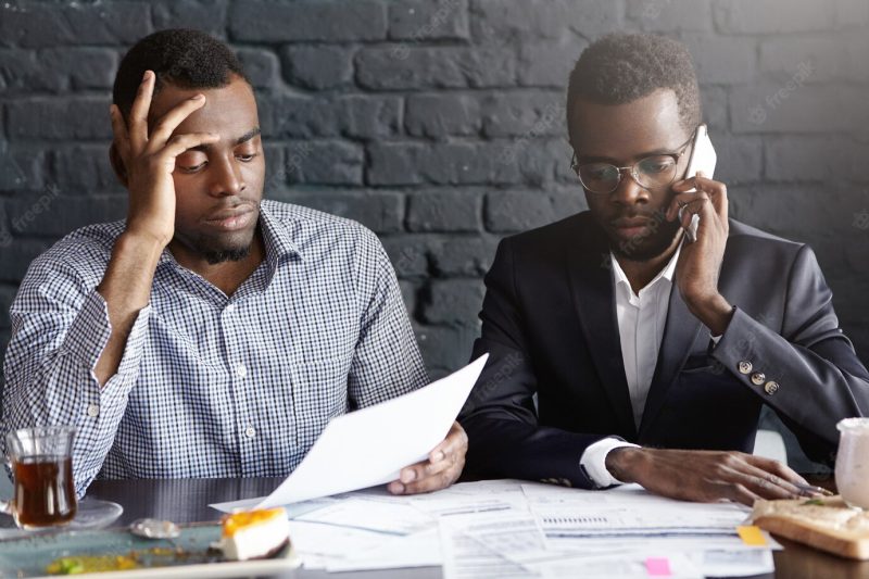 Depressed upset African-American businessman talking on cell phone Free Photo