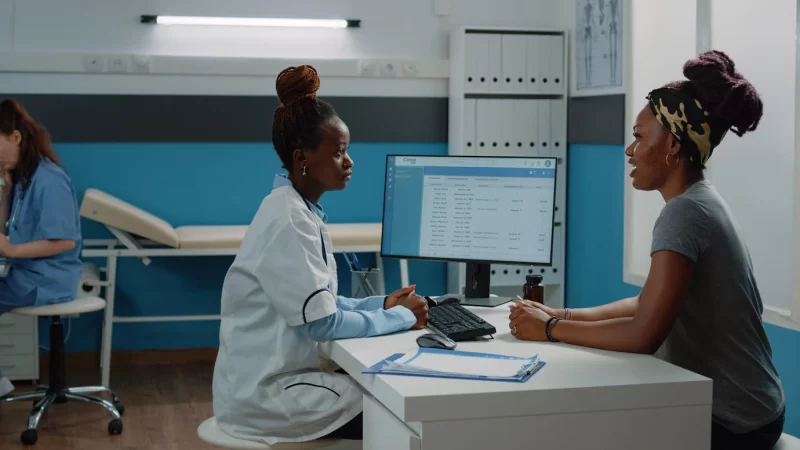 Doctor consulting young patient at checkup visit for healthcare in cabinet. woman in pain talking to medic about healing treatment and consultation. medical worker at examination Free Photo