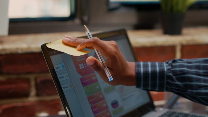 Employee putting sticky notes on laptop screen as work reminder in company office. manager using adhesive post it paper on display to remember business schedule and presentation. close up Free Photo