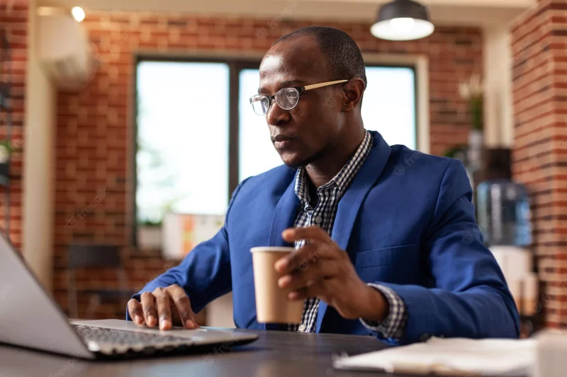 Employee using laptop to work on project planning and strategy at office job. business man working with computer on financial paperwork and surfing internet at desk. focused employee Free Photo