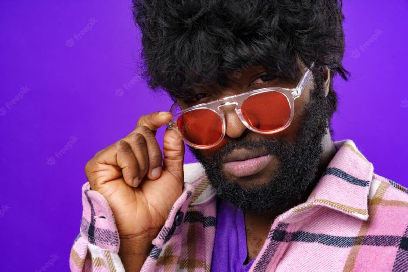 Fashion portrait of african american man in glasses against purple background Free Photo