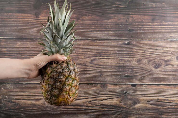 Female Hand Holding Single Fresh Pineapple Wooden Background 114579 89136