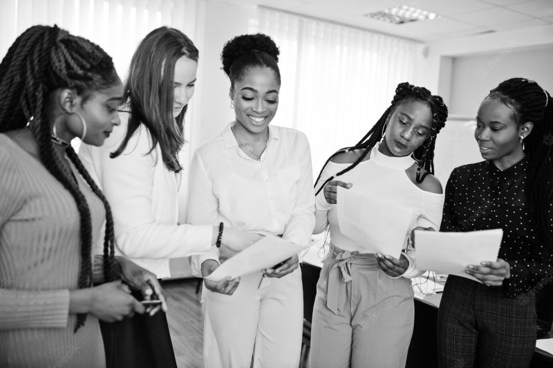 Five multiracial business women standing in the  office with papers on hands diverse group of female employees in formal wear Free Photo