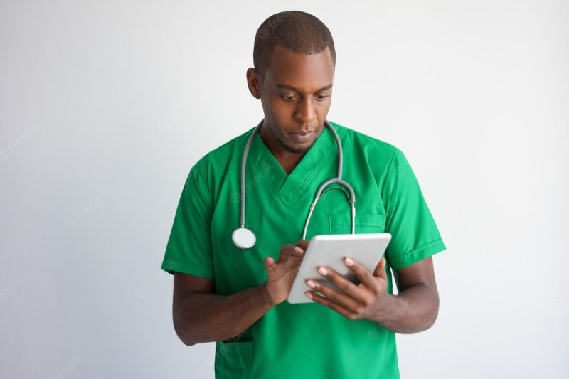 Focused black male doctor using tablet computer. Free Photo