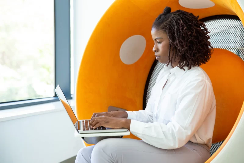 Focused woman with dreadlocks typing on laptop Free Photo