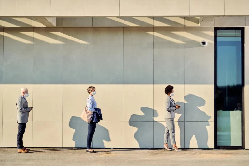 Full length of business people with protective face masks waiting in a line outdoors Free Photo