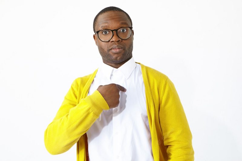 Funny Afro American guy in stylish eye wear expression shock and full disbelief to be chosen among others, pointing index finger at himself and asking: you mean me. human facial expressions Free Photo