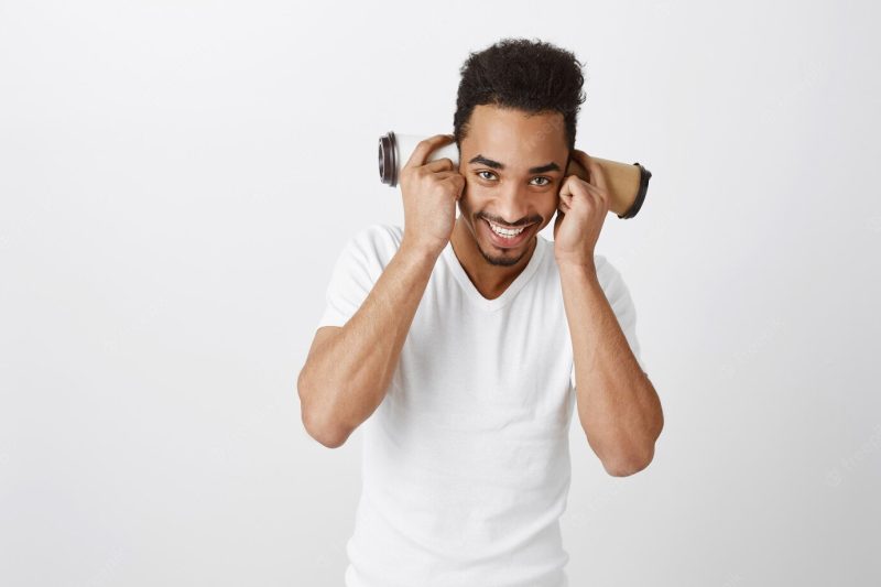 Funny handsome African American guy playing with paper cups and smiling broadly Free Photo