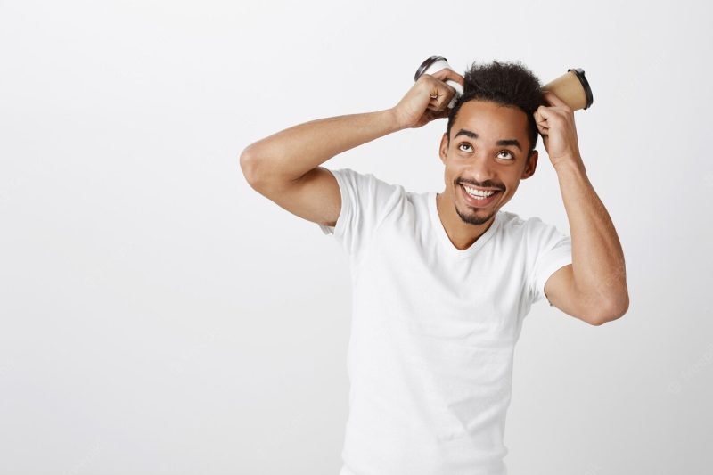 Funny handsome African American guy playing with paper cups and smiling broadly Free Photo