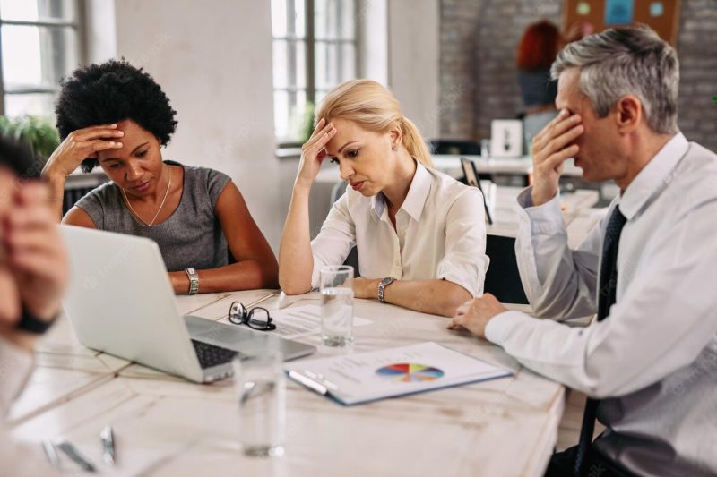 Group of business colleagues having a headache while working on laptop and trying to solve the problems during a meeting Free Photo