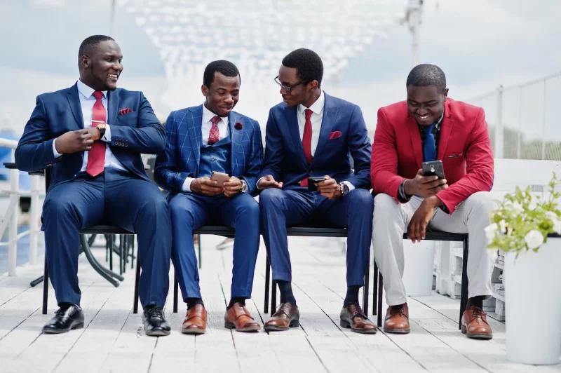 Group of four african american happy succesfull mans at suit rich black business mans sitting at chairs looking at mobile phones Free Photo