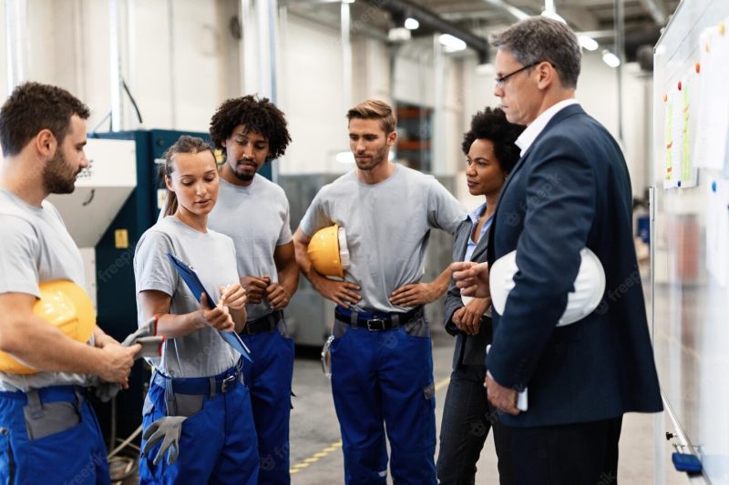 Group of workers having a meeting with company managers in a factory focus is on female worker is presenting development reports Free Photo