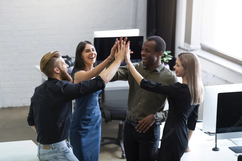 Group of young colleagues giving each other a high five Free Photo