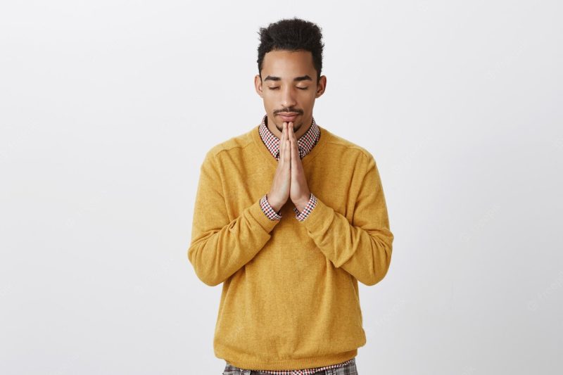 Guy needs to calm down, prepare for performance. worried attractive African-American with Afro hairstyle calming down, praying with clasped palms above chin, closing eyes, hoping or wishing relaxed Free Photo