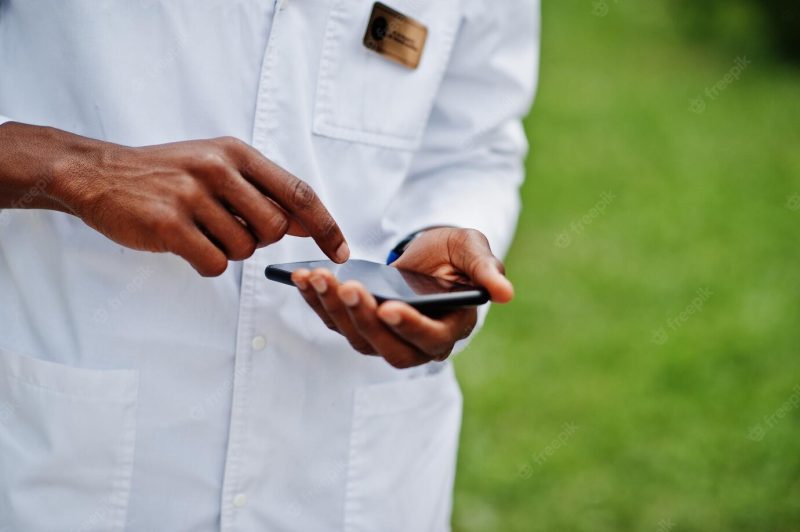 Hands of african American doctor using his mobile phone Free Photo