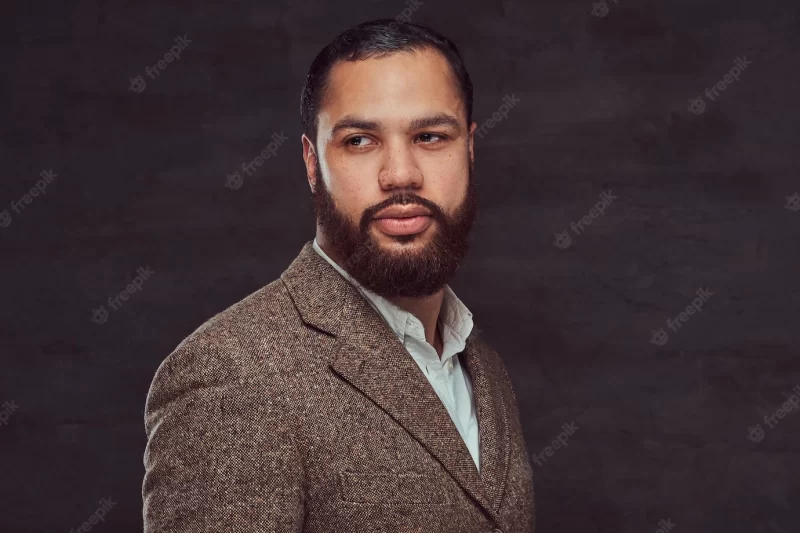 Handsome bearded african-american businessman in a brown classic jacket. isolated on a dark background. Free Photo