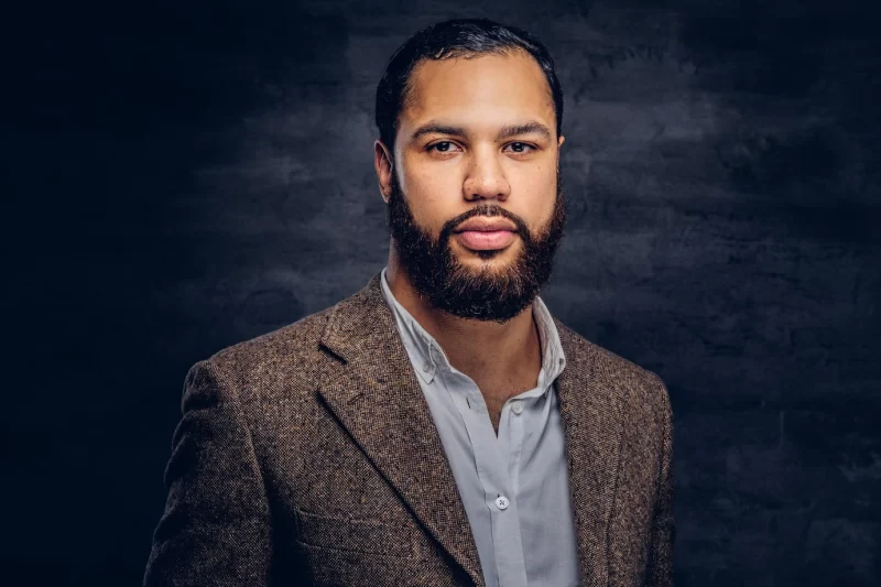 Handsome bearded african-american businessman in a brown classic jacket. isolated on a dark background. Free Photo