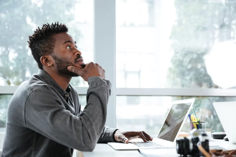 Handsome thinking serious young man sitting in office working Free Photo