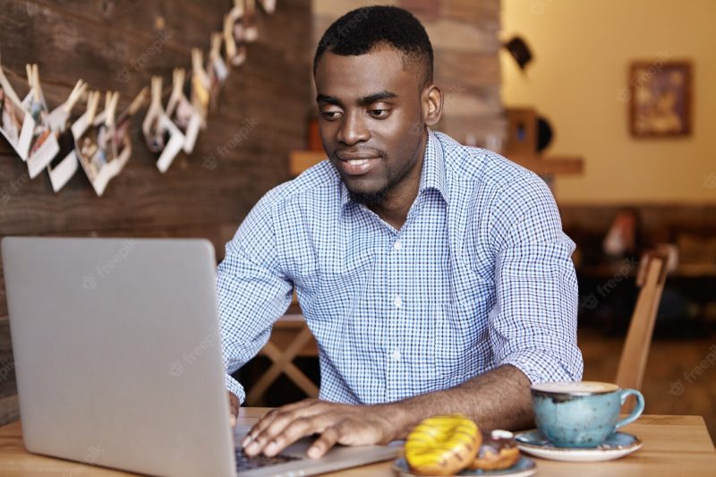 Handsome young african freelancer working on laptop computer remotely Free Photo