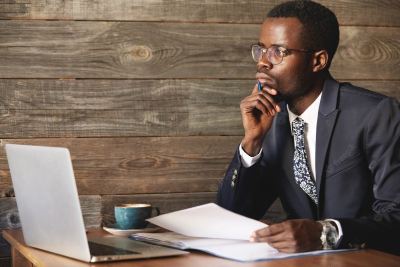 Handsome young African man wearing formal suit sitting at a coffee shop Free Photo