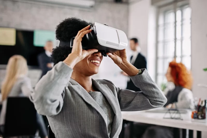 Happy African American business woman trying out virtual reality simulator at work Free Photo