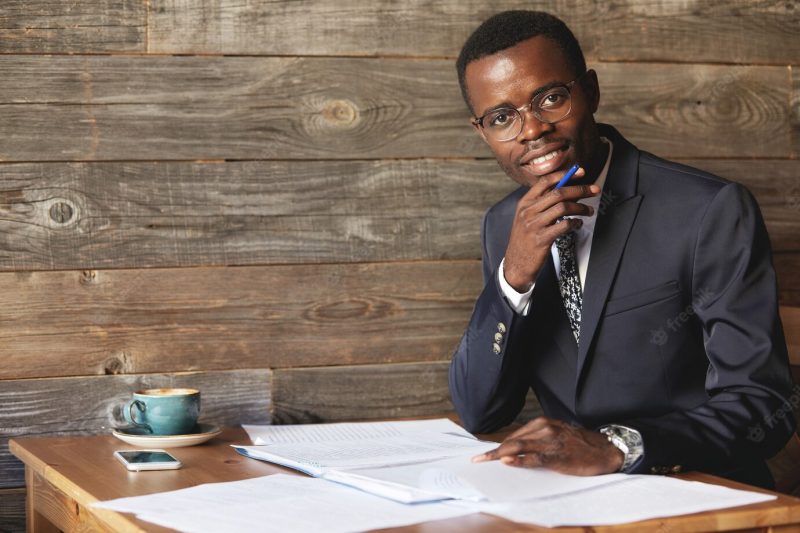 Happy african student in formal suit and glasses looking and smiling Free Photo