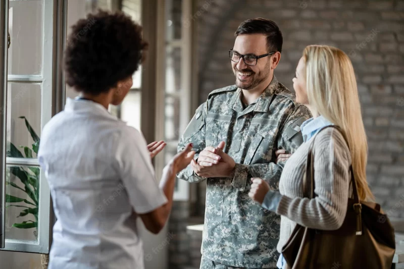 Happy army soldier and his wife communicating with African American healthcare worker while having consultations at the clinic Free Photo