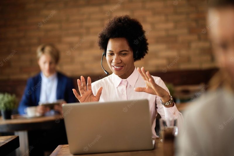 Happy black businesswoman making video call over laptop in a cafe Free Photo