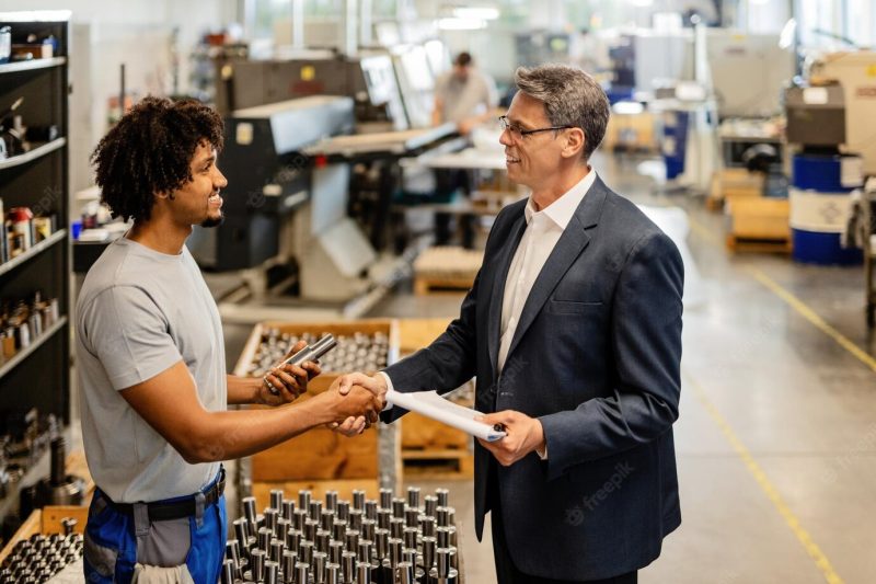 Happy businessman greeting african american steel worker while visiting industrial facility Free Photo