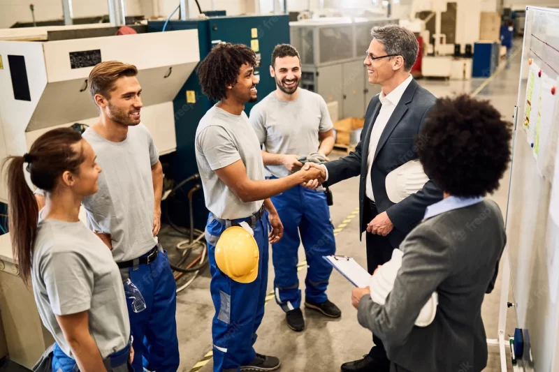 Happy corporate manager shaking hands with black worker after staff meeting in a factory Free Photo