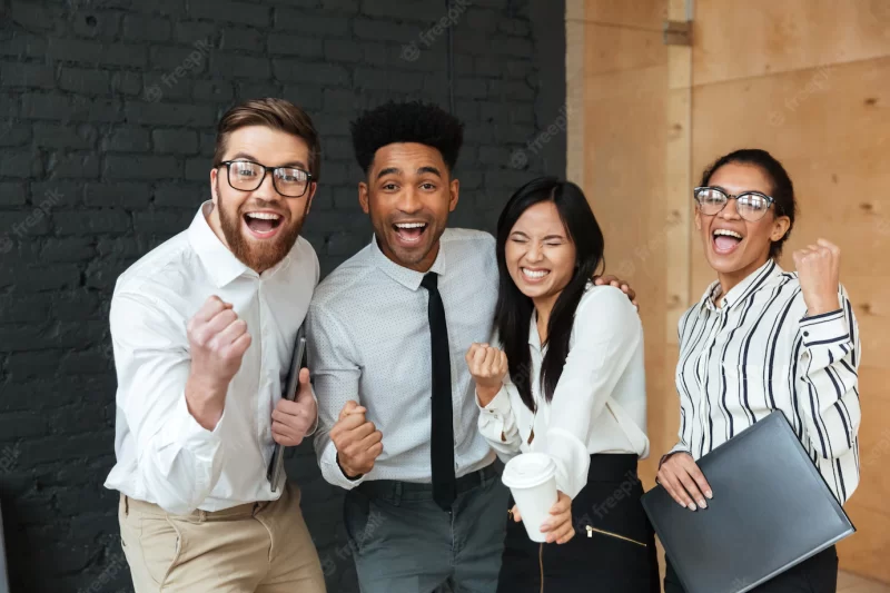 Happy excited young business colleagues make winner gesture. Free Photo