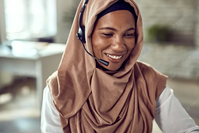 Happy islamic businesswoman wearing a headset while working in the office Free Photo