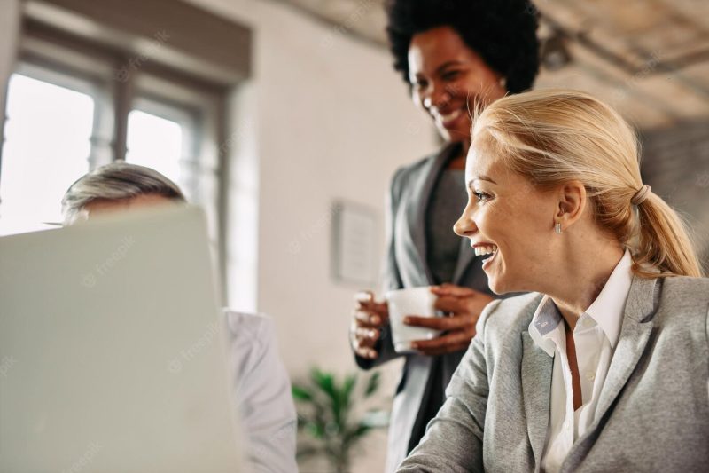 Happy mid adult businesswoman talking to her coworkers and laughing while working in the office Free Photo