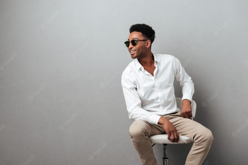 Happy young African man sitting in a chair Free Photo