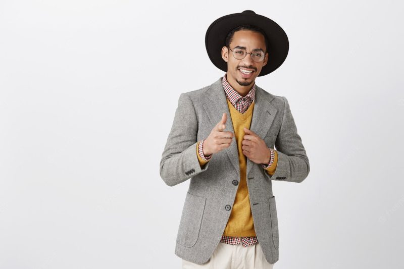 He can rely on you. portrait of satisfied confident african-american guy in black hat and stylish jacket, showing gun sign, boosting confidence near mirror before going out Free Photo