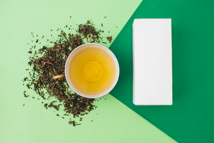 Herbs with green tea and white box on green background Free Photo