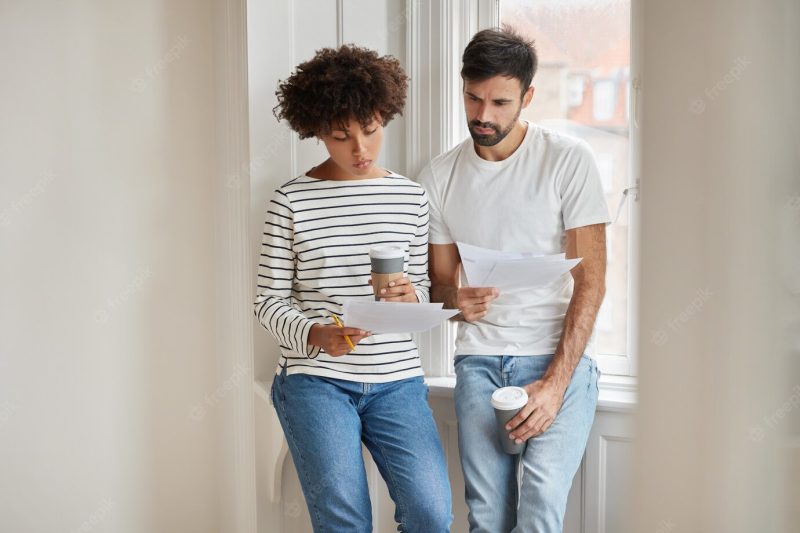 Horizontal shot of african woman, her husband study family budget, make accounting Free Photo