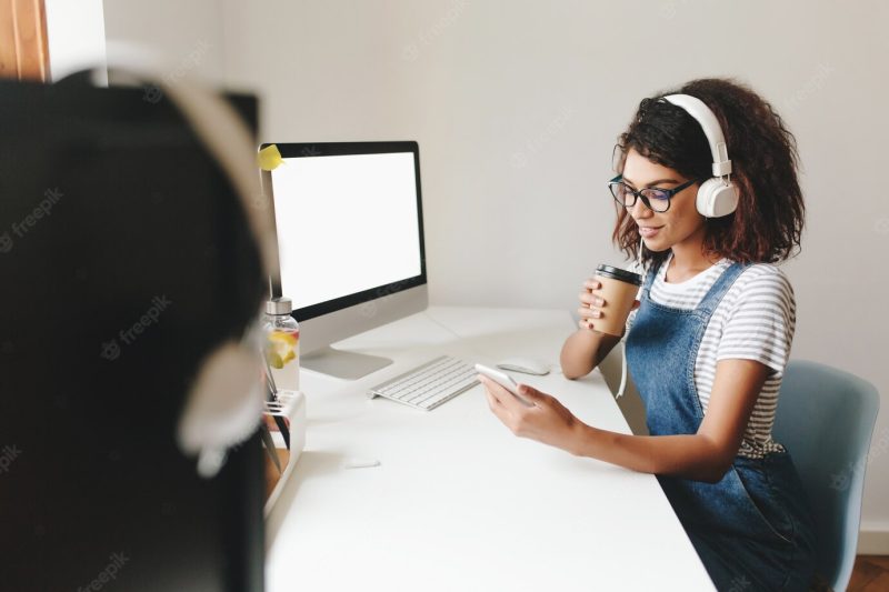 Indoor portrait of cute young woman with short hairstyle working in office with computer Free Photo