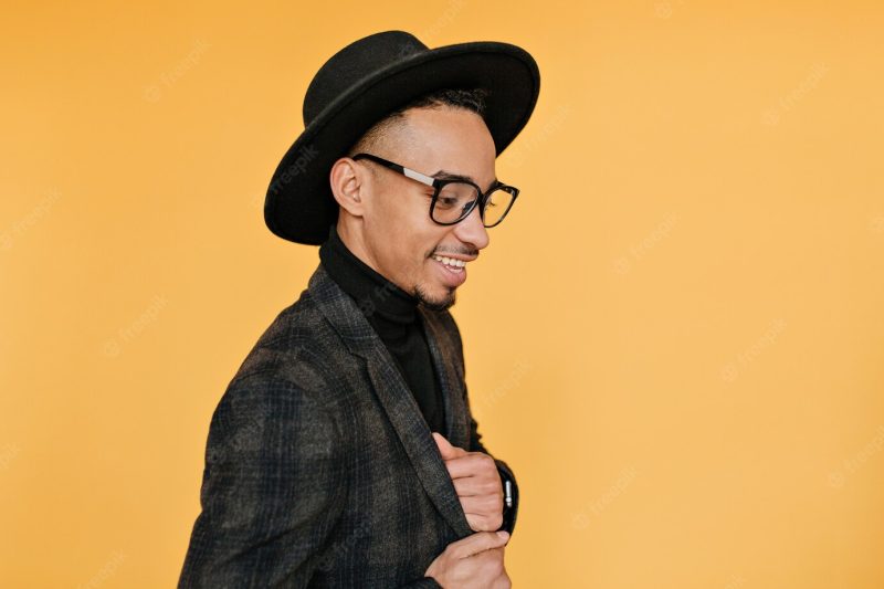 Indoor portrait of good-looking mulatto guy spending time with bright interior. photo of fashionable black male model looking down during photo shoot. Free Photo