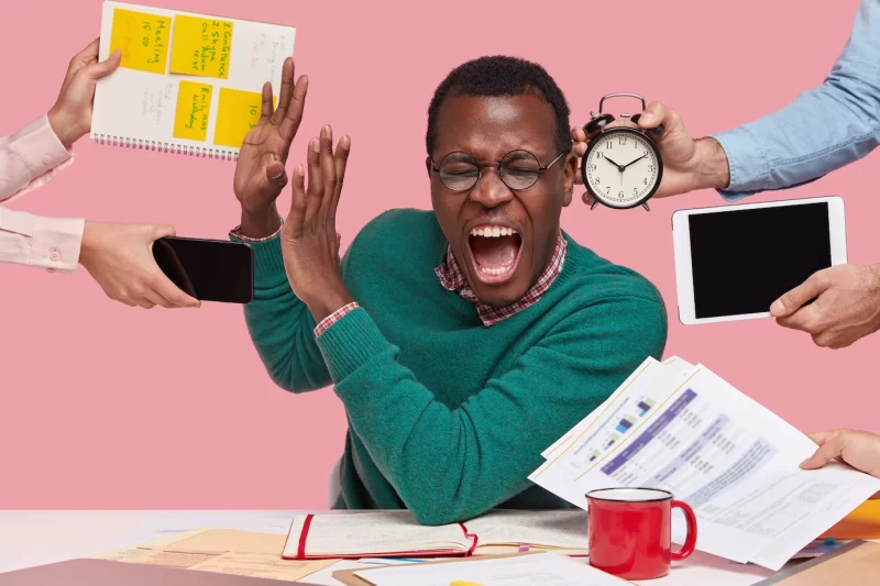 Indoor shot of desperate young Afro American man screams desperately, makes stop gesture, dressed in green sweater, busy working, isolated over pink background. people Free Photo